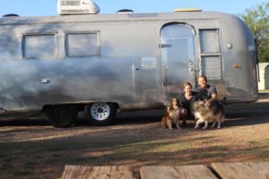 Chris and Emmelyn in front their Airstream with their dogs, a Sheltie named Dusty and a husky named Bandit. Love a dog friendly glamping trip!