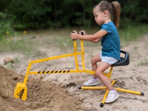 Nick's daughter playing with a toy excavator in a sand pile